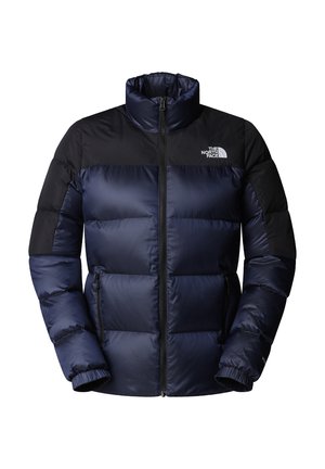 Chaqueta acolchada azul marino con cuello alto, paneles en los hombros negros, cierre con cremallera en el frente y puños elásticos; cuenta con el logo de The North Face en el pecho.