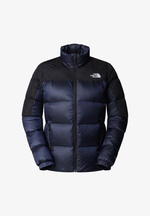 Dunkelblauer Steppjacke mit hohem Kragen, schwarzen Schulterpaneelen, durchgehendem Reißverschluss und elastischen Bündchen; auf der Brust befindet sich das Logo von The North Face.