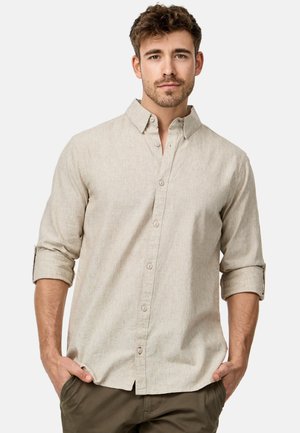 Camisa de manga larga color beige claro con cuello abotonado, botones en la parte delantera y mangas dobladas. Presenta una tela texturizada y un dobladillo recto.