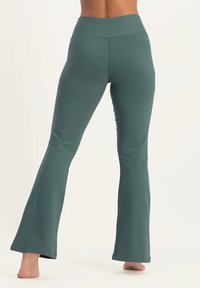 U-formade träningsleggings i en dämpad grön färg, tillverkade av mjukt, stretchigt tyg med hög midja och släta sömmar.