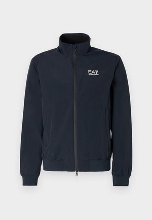 Granatowa, lekka kurtka z zamkiem błyskawicznym, wysokim kołnierzem oraz elastycznymi mankietami. Posiada białe logo EA7 na lewej piersi.