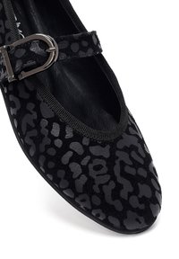 Zwarte balletflat met een luipaardprintpatroon in suède en leer. Heeft een ronde neus en een verstelbare band met een zilveren gesp.