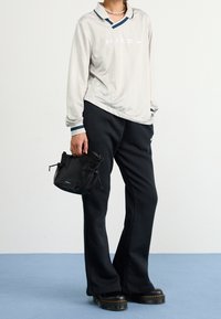 Ljusgrå långärmad Nike-tröja med blå detaljer, i kombination med svarta träningsbyxor. Har en liten svart väska med nätdetaljer.