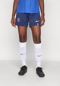 Navy soccer shorts with a Paris logo, paired with white Nike socks and black soccer shoes. The jersey features a geometric blue design.
