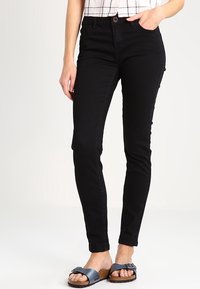 Zwarte skinny jeans met een hoge taille, gemaakt van denim. Kenmerken zijn onder andere een sluiting met een knoop aan de voorkant en zijzakken, aangevuld met platte sandalen.