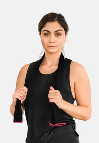 Black athletic tank top with mesh texture, held by a person with a knotted hem, featuring pink accents on the straps. Simple background.