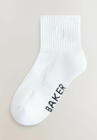 Chaussette blanche à la cheville avec bord-côte et texte noir "BAKER" sur la semelle, présentée à plat sur un fond clair.