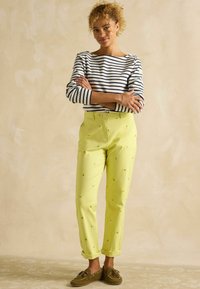 Ribadest pikkade varrukatega särk, valge ja tumesinine, koos erksa kollase püksiga, millel on sidrunite tikandid, üles keerdkäärid ja pruunid jalanõud.