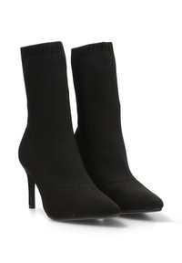 Botines de punto negros con punta afilada, tacón alto y abertura superior acanalada. Textura suave con un diseño ajustado.