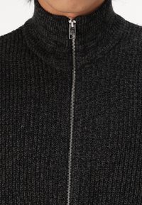 Dark gray, textured knit sweater with a high collar, featuring a full zip closure and metallic zipper. Sturdy and cozy material.