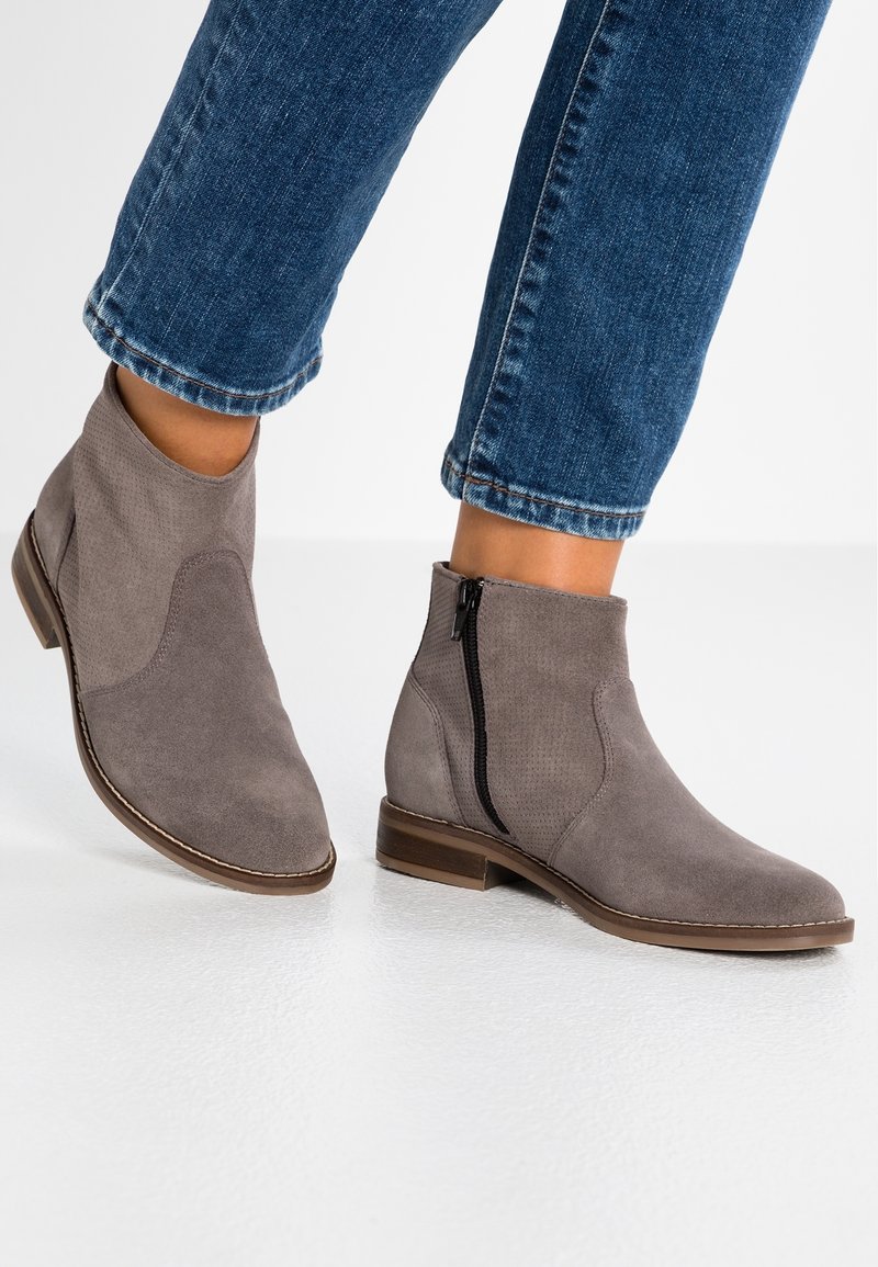 Grey suede ankle boots with a rounded toe, side zipper, and textured panels. Featured with a low heel and contrast stitching detail.
