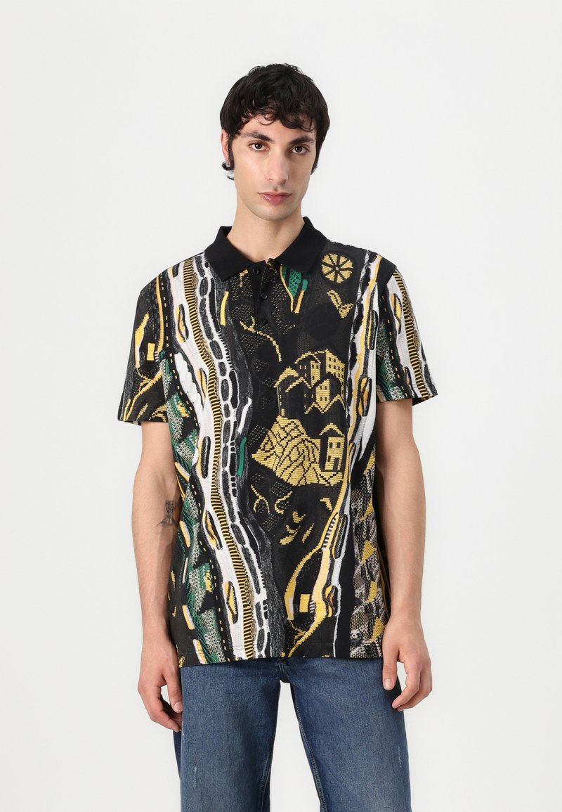 Polo shirt nera a maniche corte con un vivace motivo in verde, giallo e bianco, caratterizzata da grafiche dettagliate di case e forme geometriche.