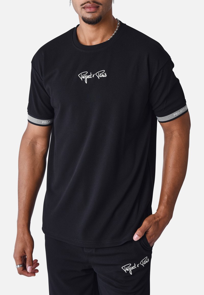 Camiseta negra de manga corta con textura acanalada, que presenta el logo blanco "Project x Paris" en el pecho y acentos grises en las mangas.