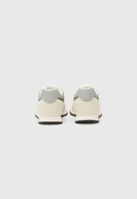 Sneakers con una toma beige e oliva, accentuazioni grigie e un design testurizzato. Presentano una suola intermedia bianca e una suola esterna in gomma nera.