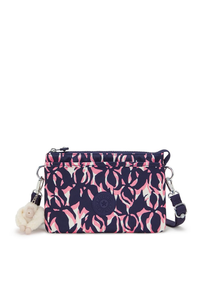 Kompaktní crossbody taška v námořnické modři s růžovým a bílým květinovým vzorem. Obsahuje zipové uzavření, pevnou rukojeť a klíčenku ve tvaru opice.