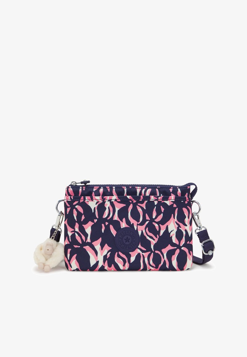Kompaktní crossbody taška v námořnické modři s růžovým a bílým květinovým vzorem. Obsahuje zipové uzavření, pevnou rukojeť a klíčenku ve tvaru opice.