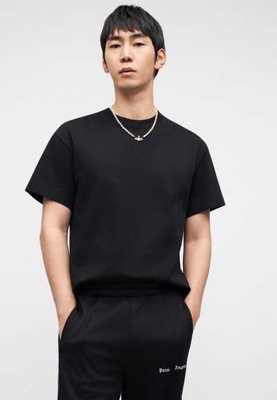 Μαύρο βαμβακερό T-shirt με κοντά μανίκια και λαιμόκοψη τύπου crew, συνδυασμένο με μαύρο παντελόνι που φέρει λευκή επιγραφή "Palm Angels". Απλή υφή.