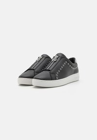Chaussures noires en cuir à enfiler avec des zips argentés, des accents cloutés et une semelle blanche. Bout rond, design minimaliste.
