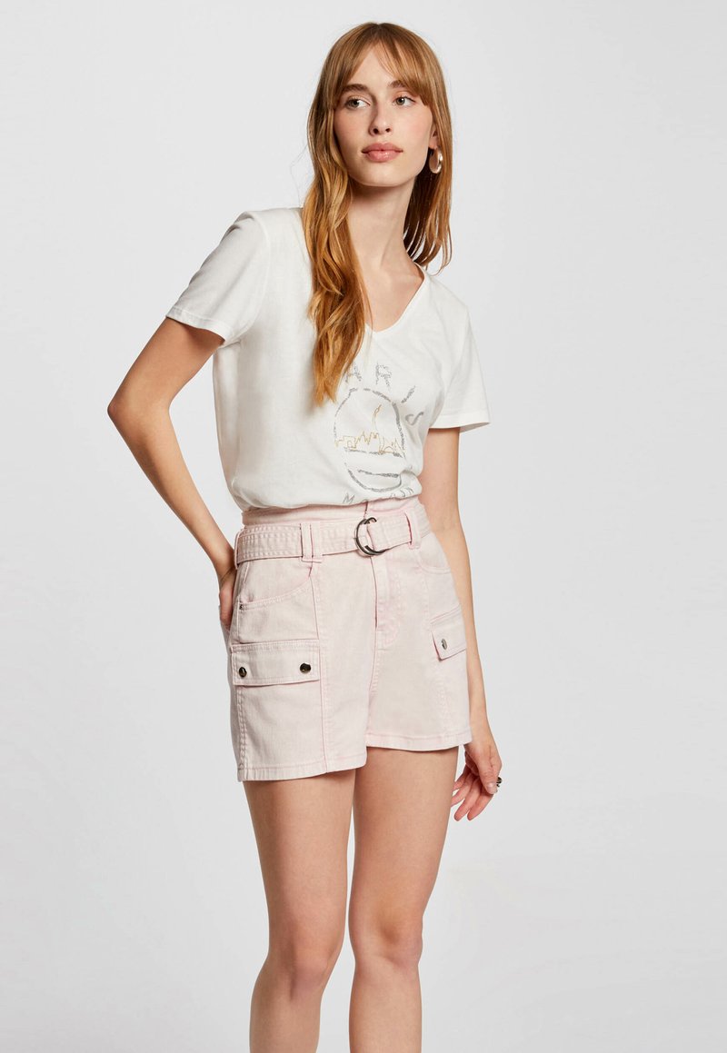 Light pink shorts with a belted waist, two front pockets, and contrasting black hardware. Paired with a white V-neck graphic t-shirt.