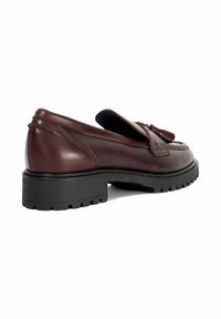 Brown leather loafers with a bow accent, low black rubber sole, rounded toe, and detailed stitching on the upper.