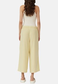 Lichtgele wijde broek met elastische tailleband, gemaakt van zachte stof; losse pasvorm met zijzakken en een zachte textuur.