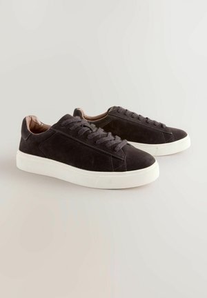 Zwarte suède sneakers met witte rubberen zolen, voorzien van een minimalistisch ontwerp, ronde neus en bijpassende veters. Zachte binnenvoering zichtbaar.