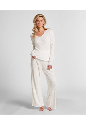 Witte loungewear set met een lange mouwen top met een scalloped halslijn en bijpassende broek met een loose fit, versierd met kleine blauwe stippen.