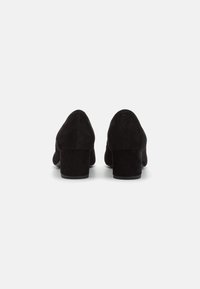 Chaussures à talons hauts en suède noir avec un bout arrondi et un talon large. L'arrière présente une texture lisse et un détail de couture subtil.