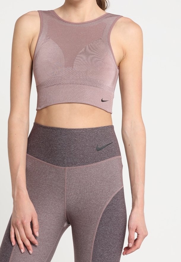 Licht mauve crop top met een textuurdesign en brede bandjes, gecombineerd met hoge roze en grijze leggings met een zwart logo-accent.