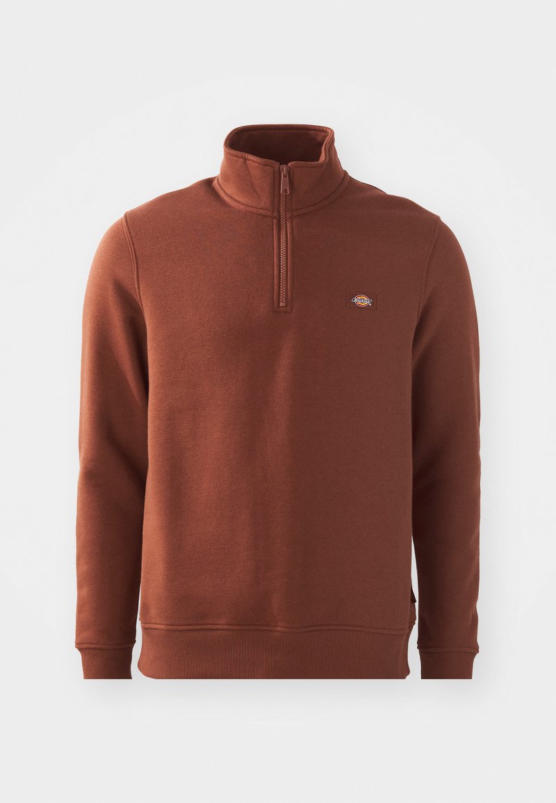 Pullover in pile marrone con colletto alto e zip a un quarto. Presenta un piccolo logo sul lato sinistro del petto e polsini e orlo a costine.