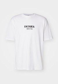 Camiseta de algodón blanca con mangas cortas y un clásico cuello redondo. Presenta una impresión negra que dice "DICKIES SINCE 1922" en el frente.