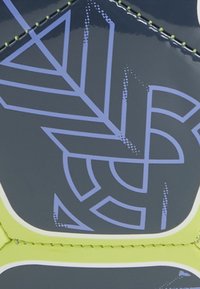 Sportinė kedai su blizgiai mėlynu paviršiumi, papuoštu violetinėmis geometrinėmis figūromis ir žaliais akcentais, papildyta kontrastingomis baltomis siūlėmis.