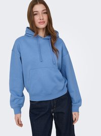 Lichtblauwe hoodie met capuchon, voorzak, geribbelde manchetten en een losse pasvorm, gecombineerd met donkere spijkerbroek.