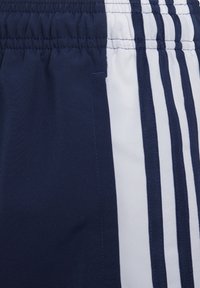 Navy athletic shorts with elastic waistband, featuring three vertical white stripes along the side and smooth, lightweight fabric texture.
