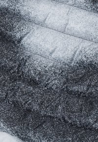 Tessuto imbottito in tonalità di grigio e nero, con una superficie testurizzata caratterizzata da un motivo maculato e cuciture trapuntate.