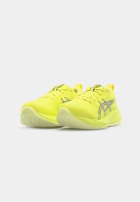 Baskets de sport jaunes fluo avec un dessus texturé, des accents réfléchissants, une semelle rembourrée et un design épuré pour la performance.