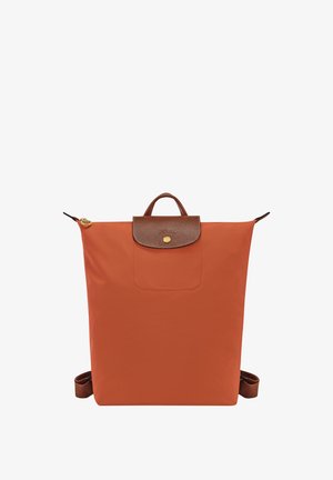 Oranger Stoff-Rucksack mit einem braunen Lederklappen, goldenen Beschlägen und einem oberen Griff, ausgestattet mit verstellbaren Schulterriemen und einer Vordertasche.