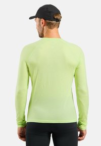 Long-sleeve athletic shirt in bright lime green, made of lightweight fabric with a textured finish. Features raglan sleeves and a crew neck.