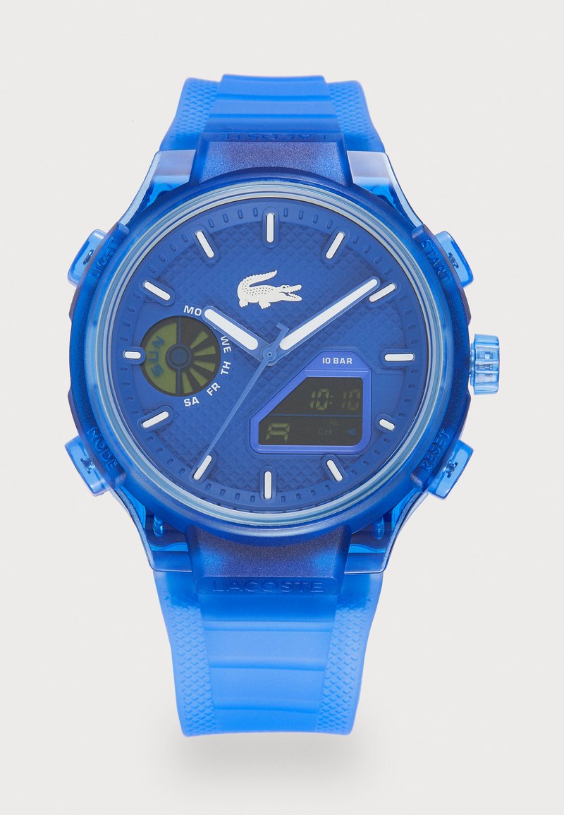 Montre en plastique bleu avec affichage numérique et analogique, cadran bleu texturé, marqueurs d'heure blancs et logo crocodile. Le bracelet présente un motif nervuré.