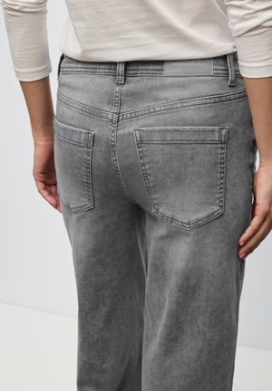 Grå denimjeans med avslappnad passform, med fyra fickor och subtila urtvättning. Etiketten i midjan läser "favoritjeansen alla tider."