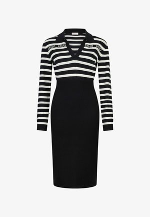 Gebreide jurk met zwart-witte horizontale strepen, een V-halskraag, lange mouwen en decoratieve accenten op de manchetten. Getailleerd silhouet.