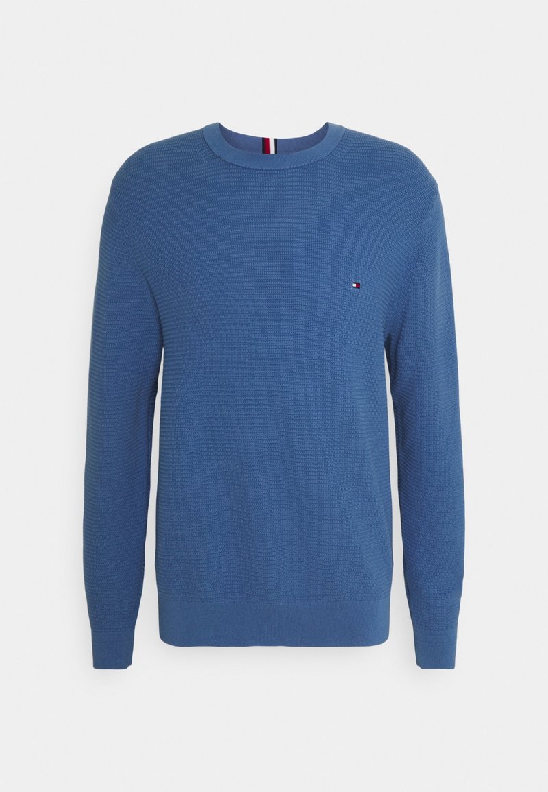 Pull bleu en maille à manches longues avec col rond, motif texturé, poignets et ourlet côtelés, et petit logo rouge, blanc et bleu sur la poitrine.