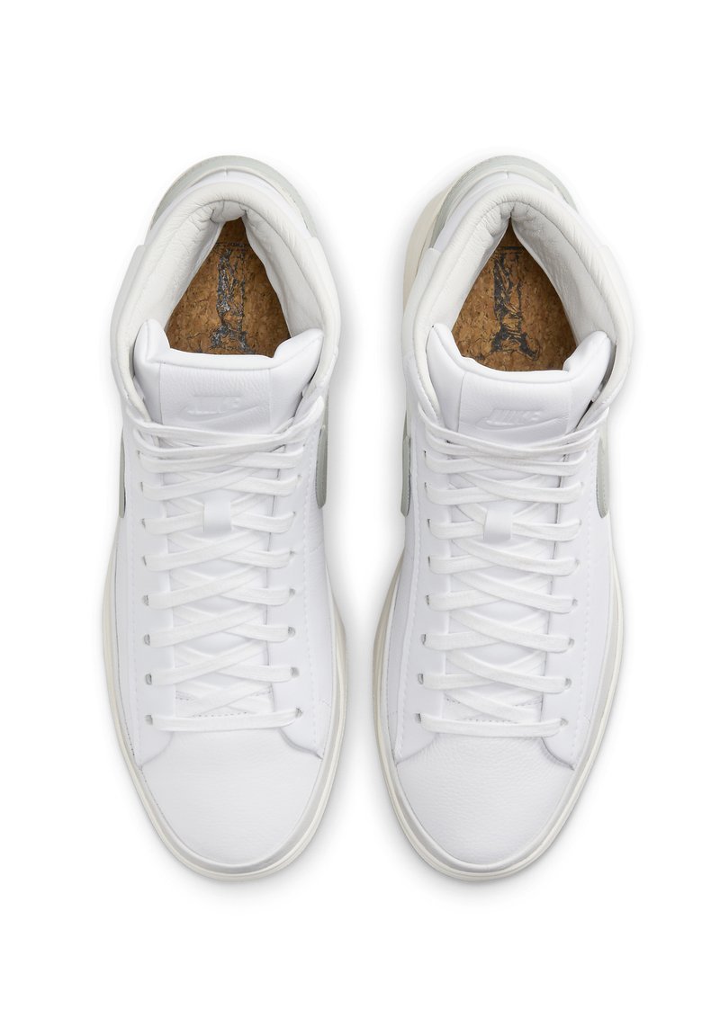 Sneakers alte bianche con esterno in pelle liscia, soletta in sughero testurizzato e sottili accenti grigi sui lati. Presentano lacci tradizionali.