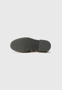 Brown patterned shoe sole with a rounded shape, made from rubber. Textured surface with horizontal grooves for traction. Flat heel section.