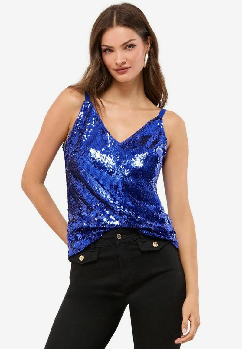 Sinine sädelevate sequinsidega tank Ülikond, millel on v-kaelus, õhukesed rihmad ja vormiv disain, koos mustade kõrge vöökohaga pükstega, millel on kaunistatud nööbid.