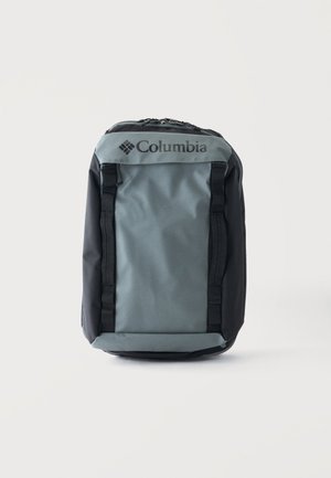 Γκρι και μαύρο σακίδιο Columbia με επάνω φερμουάρ και μπροστινούς ιμάντες, όρθιο σε λευκό φόντο.