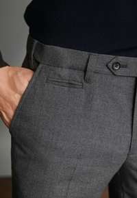 Graue maßgeschneiderte Hosen aus strukturiertem Stoff. Verfügt über einen geraden Schnitt, einen Knopfverschluss und eine seitliche Tasche mit schlanker Optik.