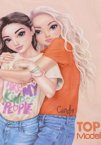 T-shirt rosa chiaro con due personaggi dei cartoni animati che si abbracciano. Uno indossa una maglietta bianca con testo colorato; l'altro ha un top arancione.