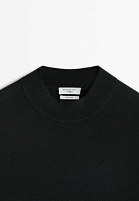 Maglione nero lavorato a maglia con scollo rotondo e bordi a coste. Etichetta visibile all'interno che identifica il marchio. Texture liscia, design casual.