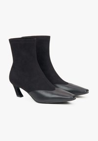 Czarne botki za kostkę łączące zamsz i skórę, z wydłużonym noskiem i geometrycznym obcasem, charakteryzujące się gładką teksturą i eleganckim wzornictwem.
